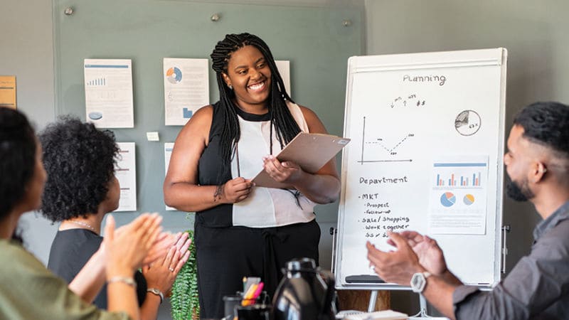 A Black woman and a Hispanic woman sitting at a conference table looking at documents together
