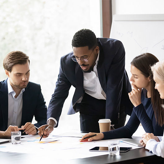 Four coworkers in an office collaborating around a conference table. 