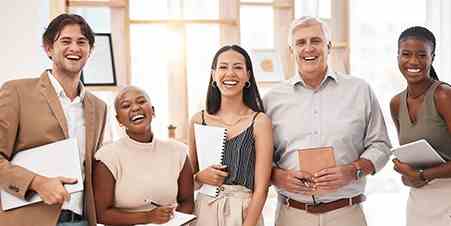 Two male and three female coworkers smiling and holding notebooks or tablets
