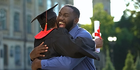 Black father excitedly hugging their child at their college graduation