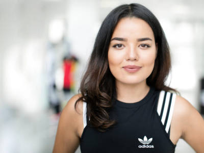 Closeup of an Asian woman looking at the camera wearing a black and white Adidas athletic top