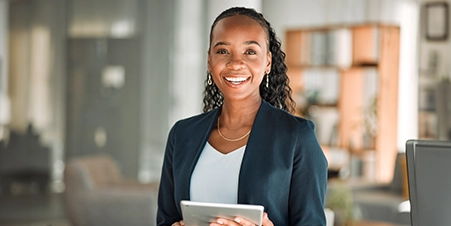 Closeup of a black female holding a tablet and smiling at the camera