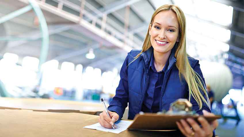 Female facilities manager reading information from a clipboard and writing on a piece of paper. 
