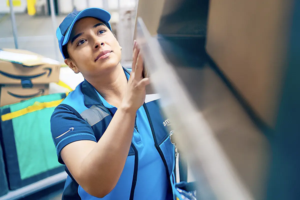 Hispanic female employee repairing a metal panel in a warehouse.