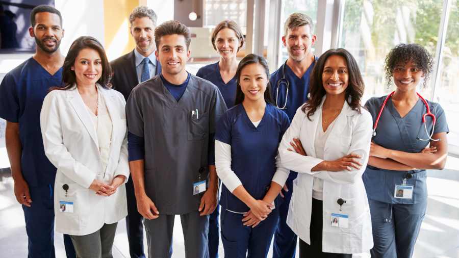 Multi-racial group of female and male Rochester Regional Health team members, some wearing scrubs and stethoscopes, and some wearing lab coats